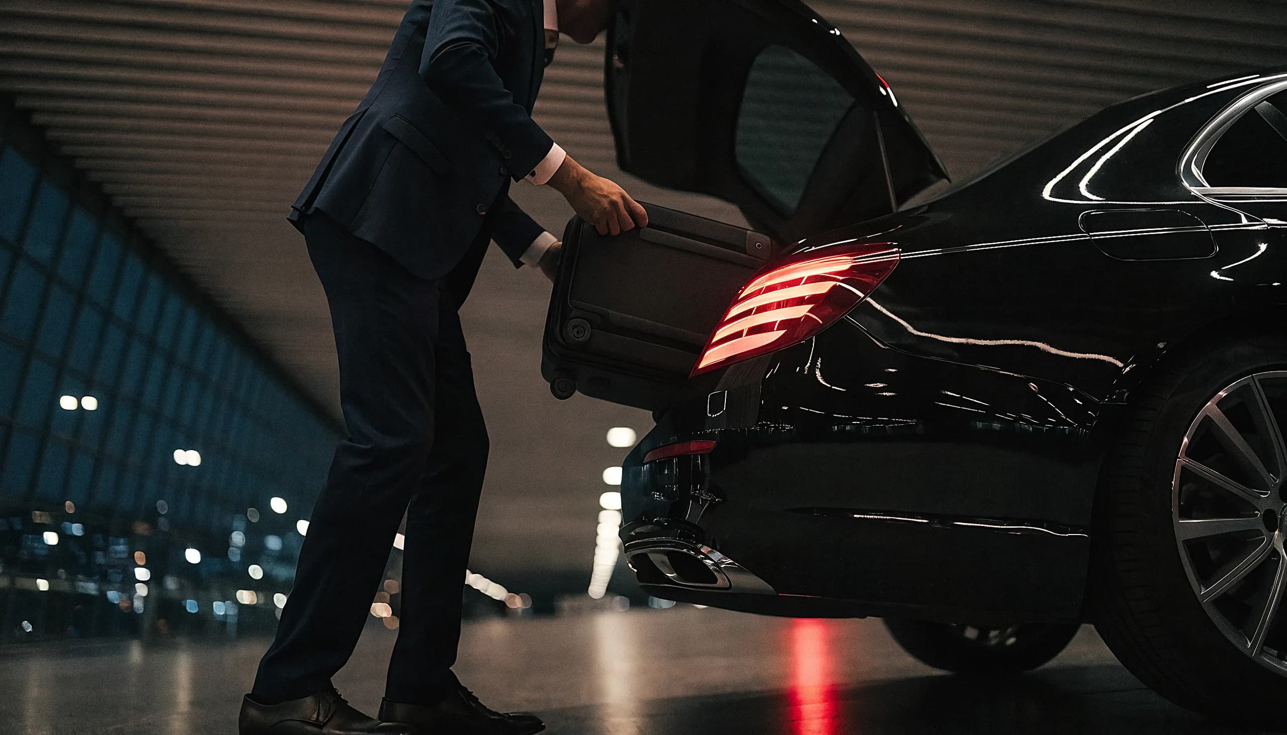 Chauffeur loading a suitcase into the boot of a luxury car