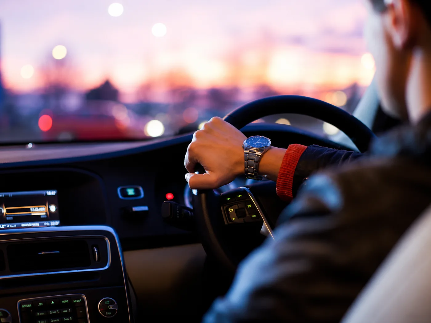A chauffeur driving through the city at dusk