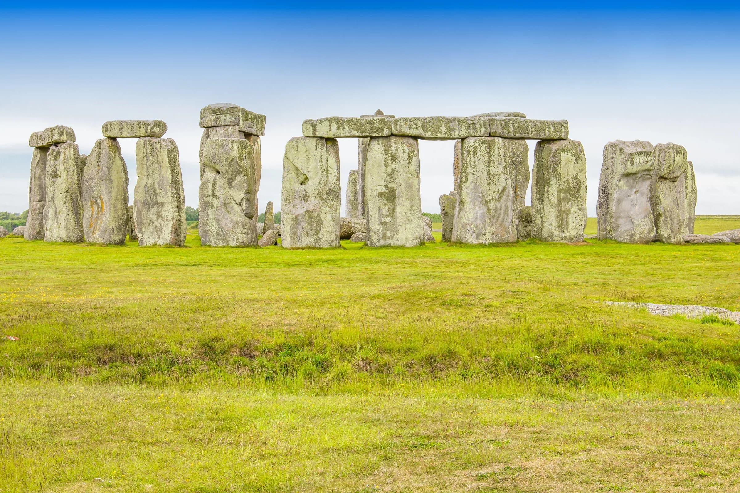 The stone circle at Stonehenge on open grassland under a blue sky
