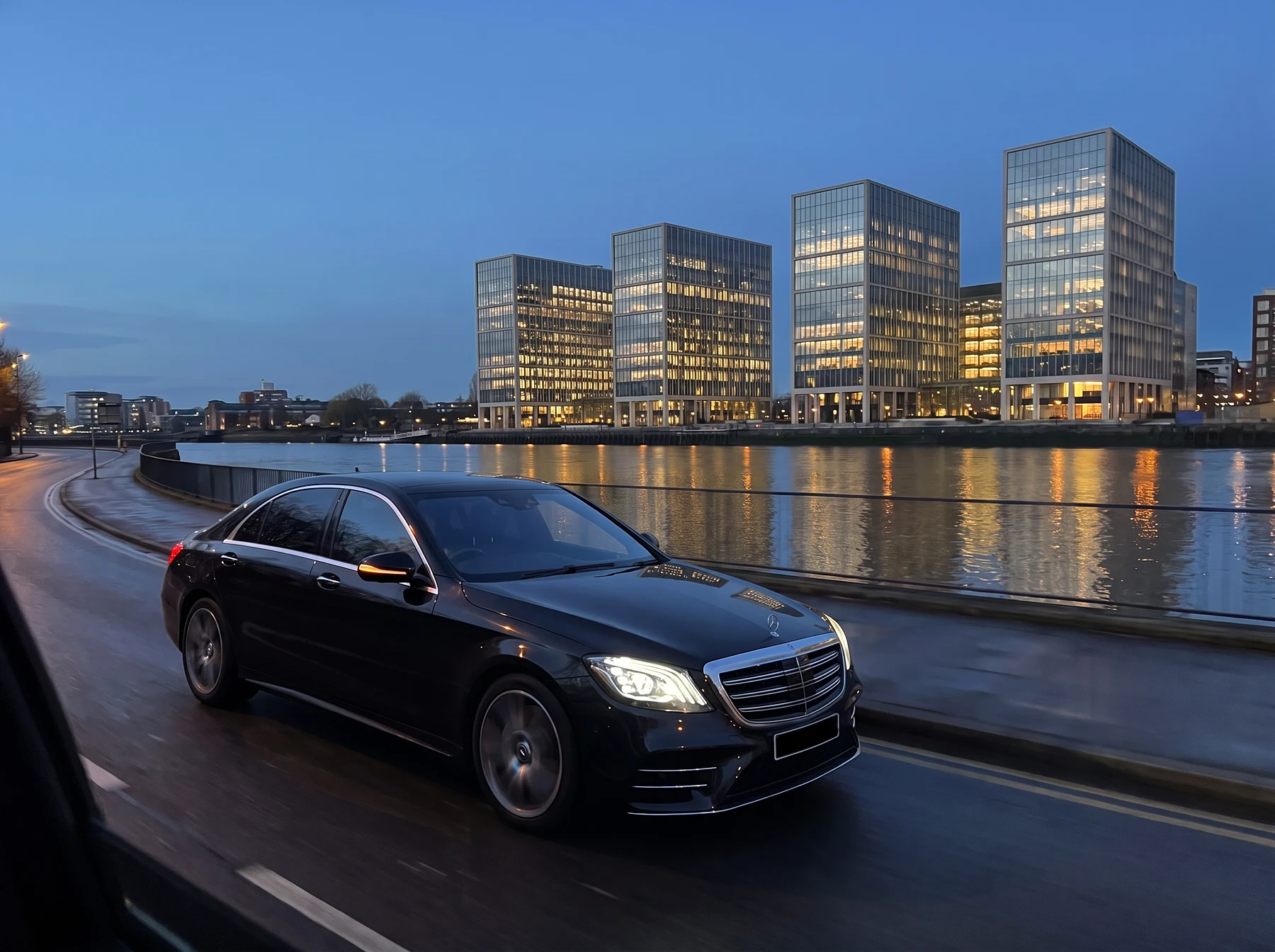 Chauffeur-driven car heading towards the Canary Wharf towers at dusk