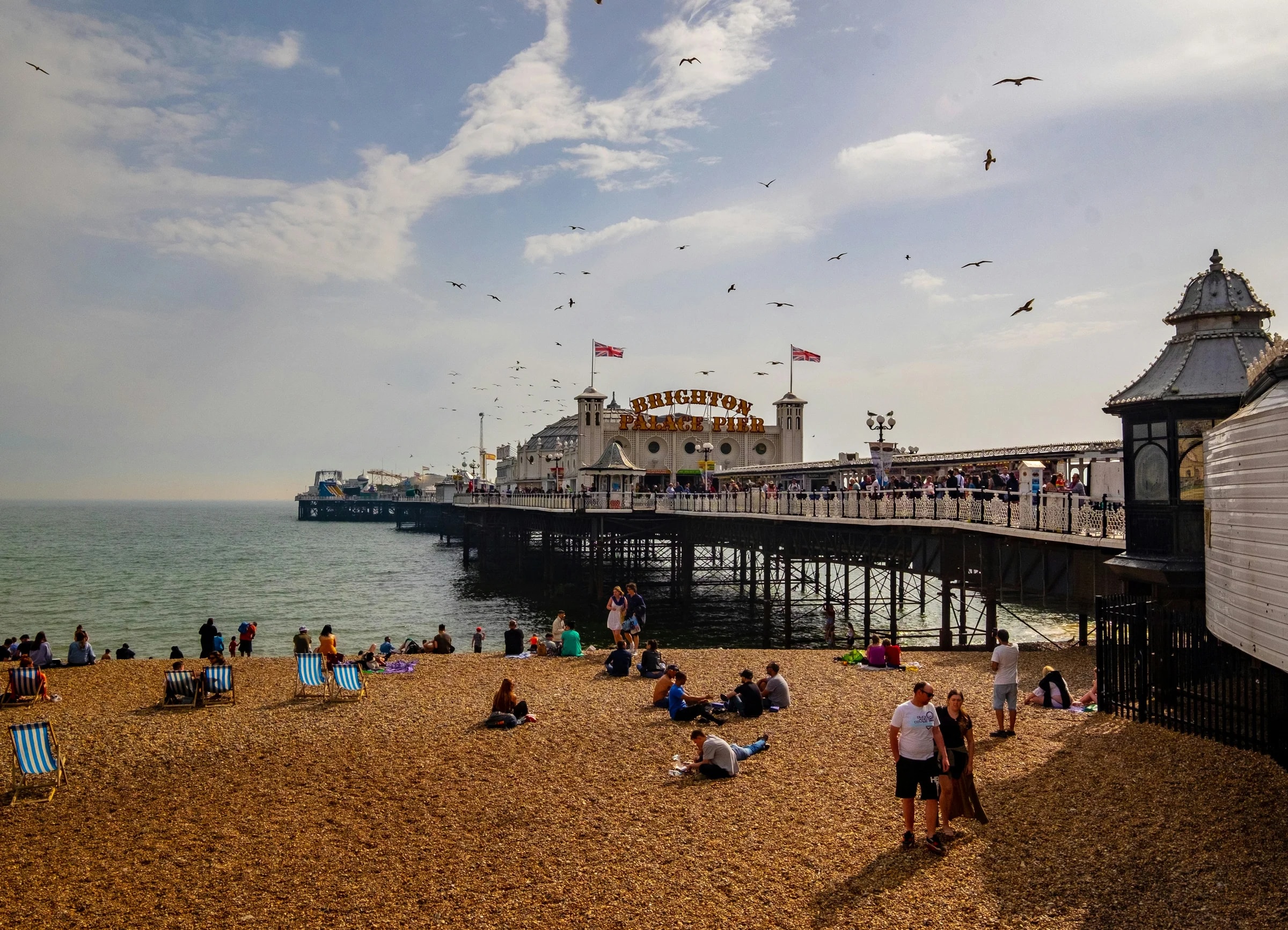 Brighton Palace Pier on a sunny day, its sign and Union flags above the shingle beach