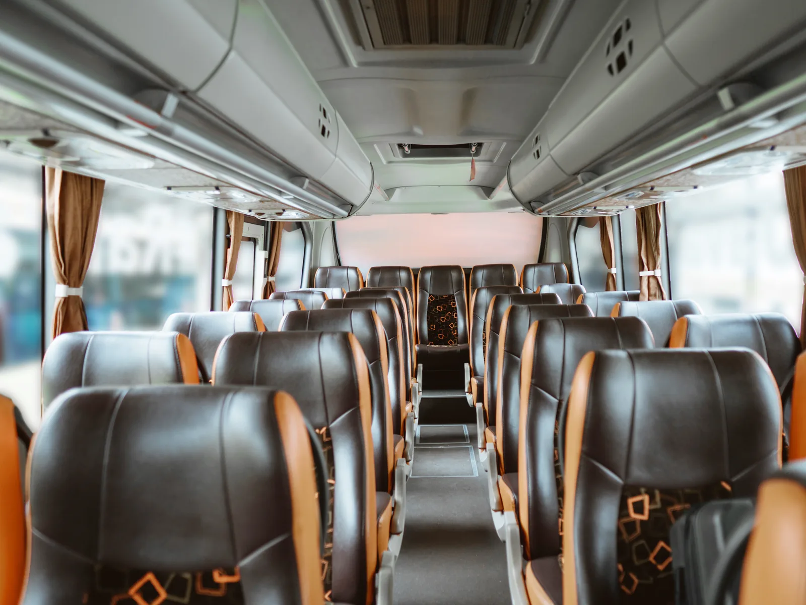 Rows of reclining leather seats inside an executive coach cabin