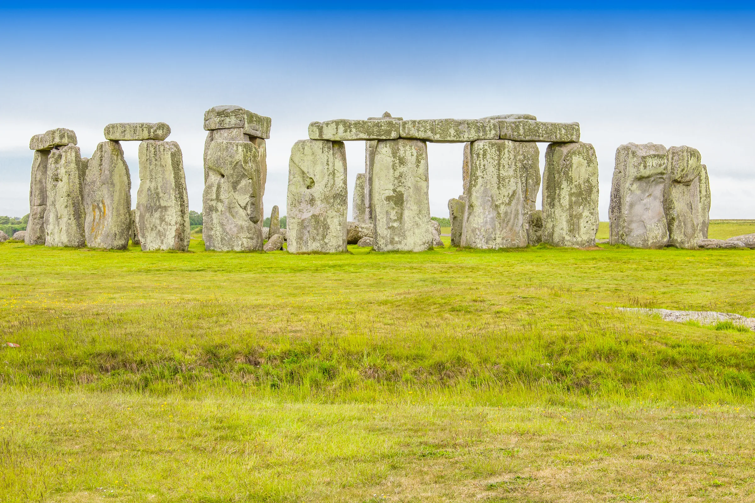 The standing stones of Stonehenge on open turf under a blue sky