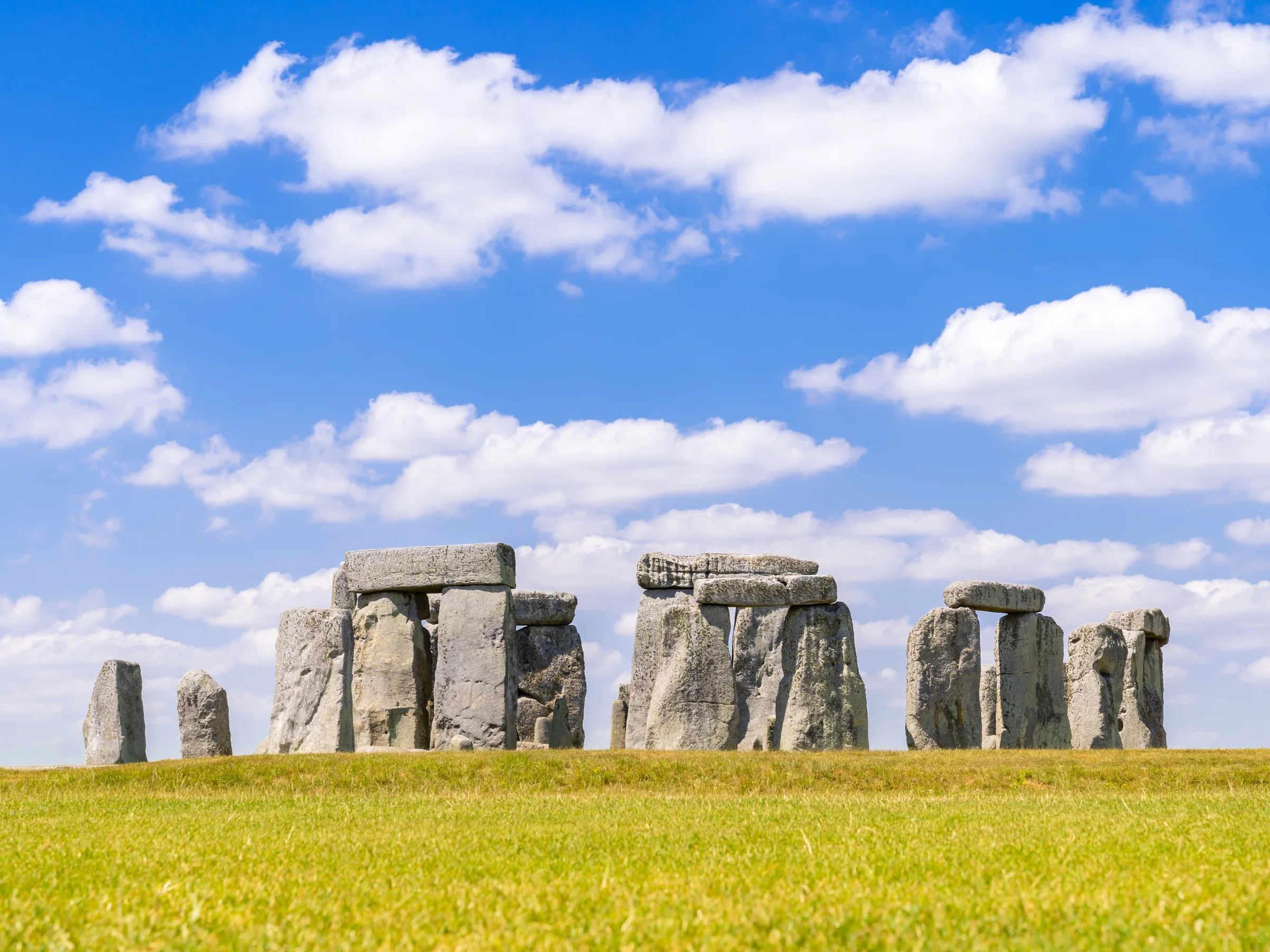The standing stones of Stonehenge under a blue sky with white clouds